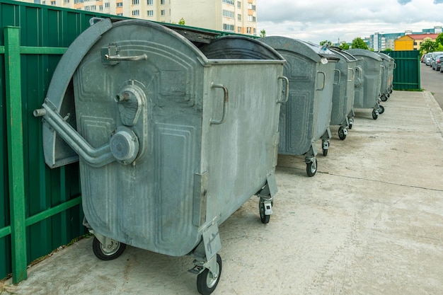 Modern metal containers for separate garbage collection Garbage cans in the city on the background of a house Environmental disaster problems of waste removal collection and disposal in a big city