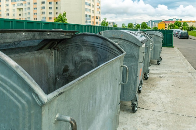 分別ごみ収集用の現代の金属容器 家の背景にある都市のごみ箱 大都市での廃棄物除去収集と処分の環境災害問題