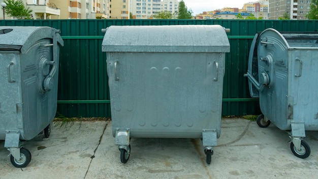 Modern metal containers for separate garbage collection Garbage cans in the city on the background of a house Environmental disaster problems of waste removal collection and disposal in a big city