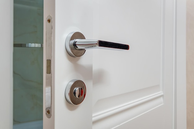 Modern metal door handle on white wooden door in interior knob
closeup elements door handle fittings for interior design