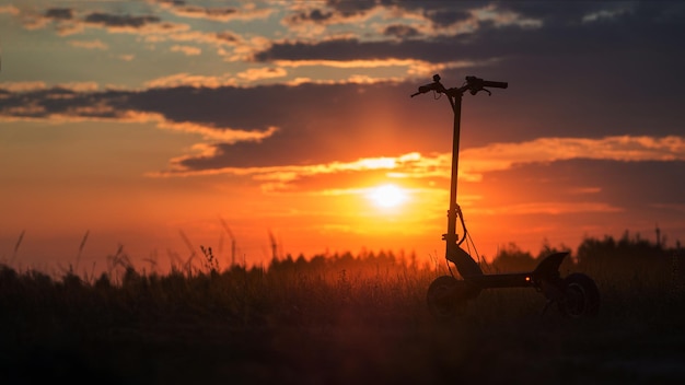 Foto modern milieuvriendelijk vervoer elektrische scooter foto silhouet bij zonsondergang selectieve focus kopieerruimte