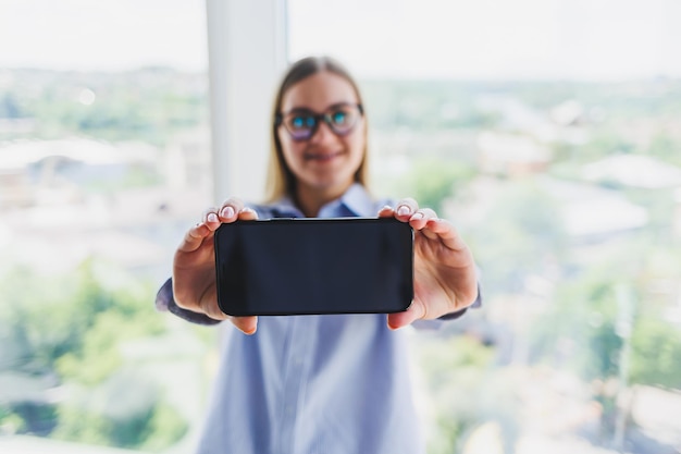 Современный мобильный телефон с черным экраном держится в руках женщины женскими руками со смартфоном крупным планом