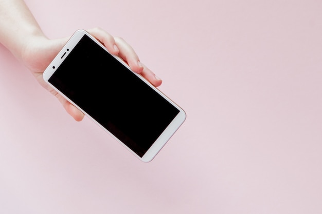 Modern mobile phone in a woman's hand on pink 