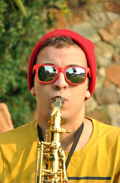 Modern musician posing with his saxophone in the garden