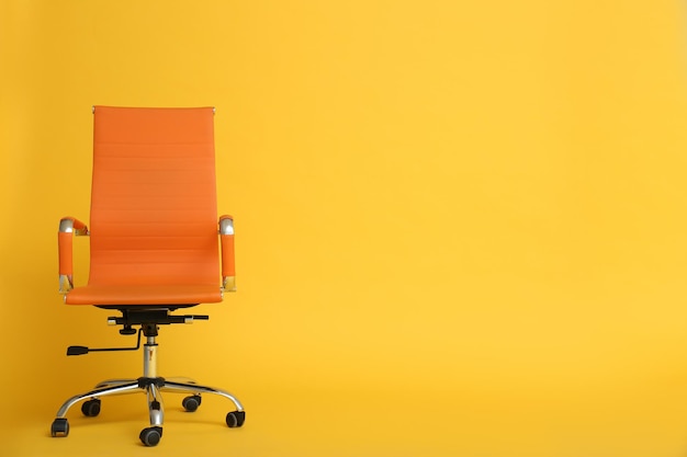 Modern office chair on yellow background space for text