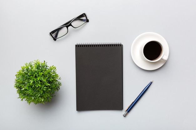 modern office desk table with notebook and other supplies with cup of coffee blank notebook page for you design top view flat lay
