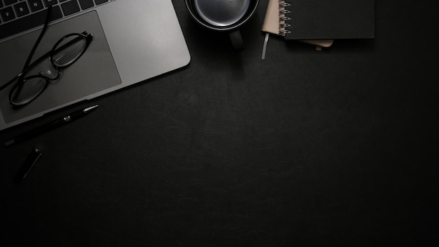 Modern office desk with laptop computer and copy space on black background top view