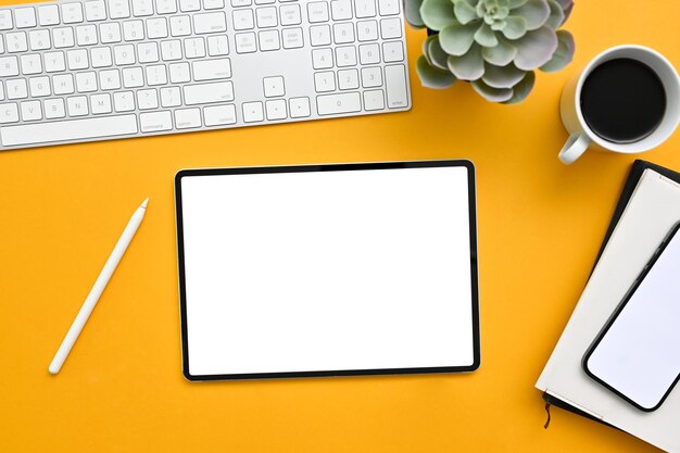 Современное рабочее место офисного стола на желтом фоне с макетом белого экрана цифрового планшета