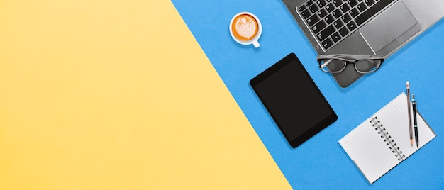 Posto di lavoro desktop ufficio moderno con laptop, notebook, tablet, caffè caldo con lo spazio della copia