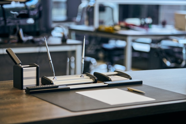 Modern office work place in large corporation. Comfortable work table with stationery, leather computer chair.