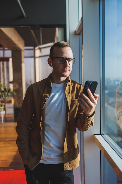 Modern office worker using smartphone app for service consultation in modern workspace man talking on the phone Remote work male freelancer