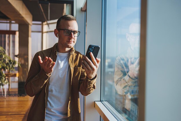 Modern office worker using smartphone app for service consultation in modern workspace man talking on the phone Remote work male freelancer