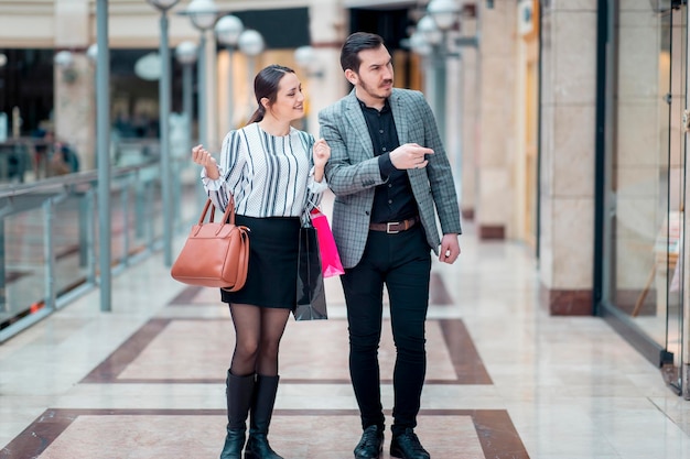 Modern ogend stel in een winkelcentrum dat ze aan het kijken zijn en naar de vitrine wijzen