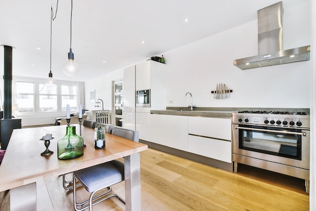 Photo modern open plan kitchen with white cabinets and dining table in studio room with sofa and fireplace