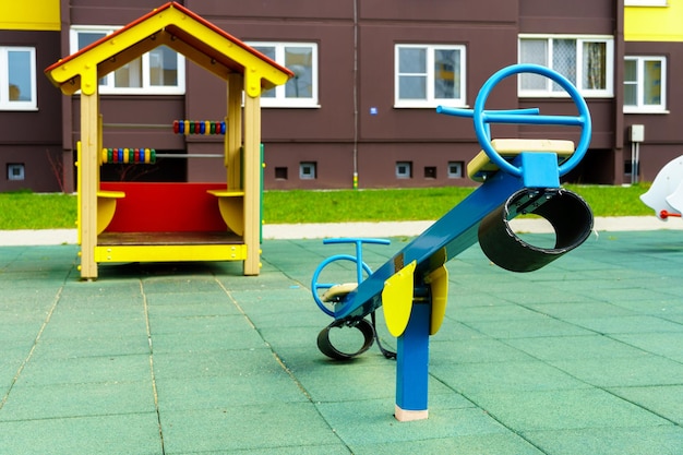 A modern outdoor playground in the courtyard of a building Colorful children's swings and slides for recreation and games are installed Playground on the background of residential buildings