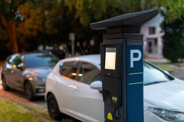 modern parking meter next to parked cars on the street parking ticketing in urban area concept