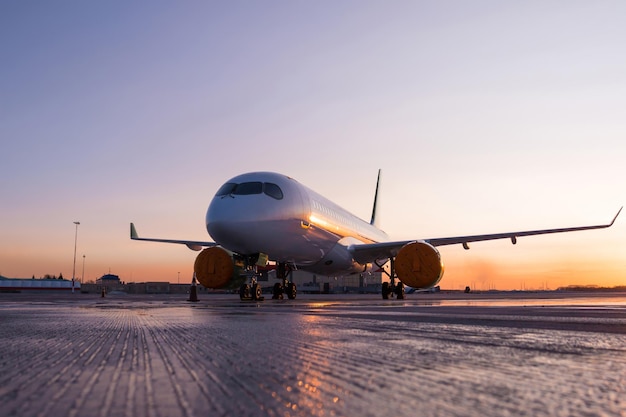 風光明媚な夕日を背景に空港エプロンにある現代の旅客機