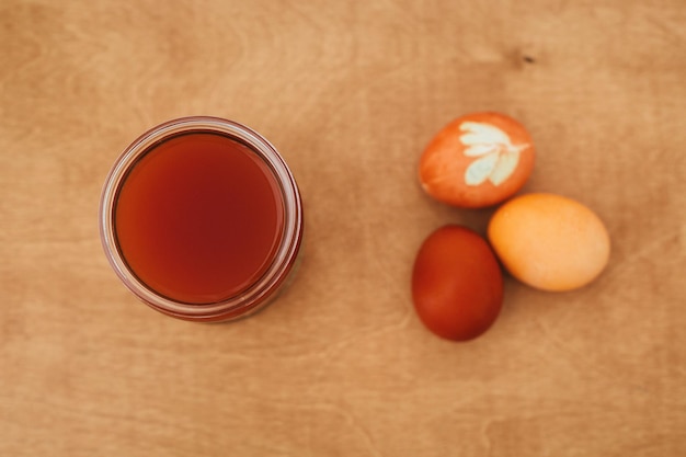 Modern pastel yellow and orange easter eggs painted with onion or turmeric glass jar with orange color Zero waste holiday Organic ingredients Natural dye easter eggs on wooden table