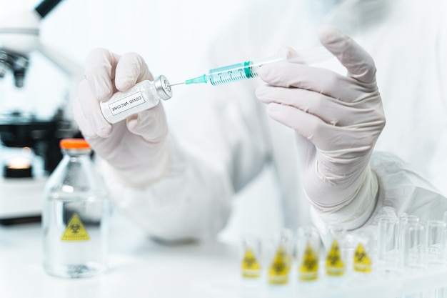 Modern pharmacy. Professional scientist sitting at his workplace while taking sample of new vaccine