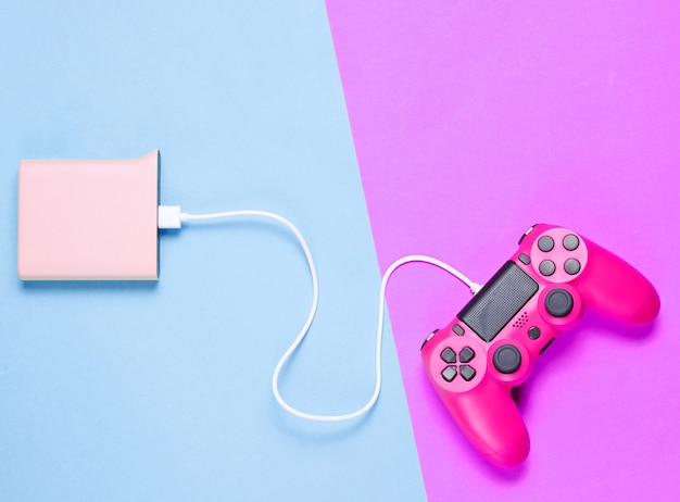 Modern pink plastic gamepad charging from power bank