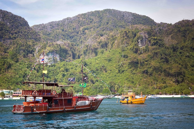 Modern pleasure tourist boat stylized as a pirate ship Against the background of a rocky shore