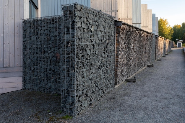 Modern privacy fence made of gabion galvanized steel grid with granite stones