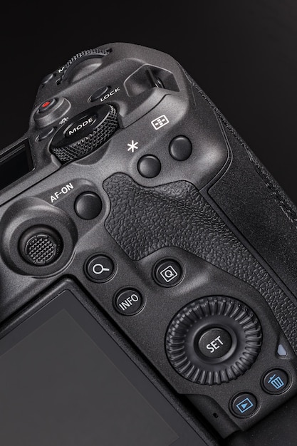 Modern professional black digital photo camera controls buttons dials wheels screens and joystick closeup macro view