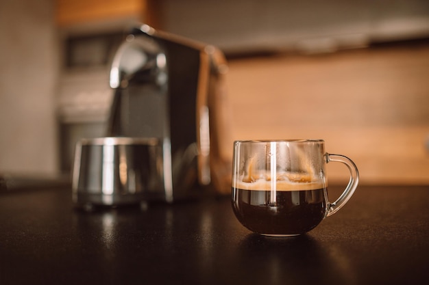Чашка современной профессиональной кофемашины эспрессо на кухонном столе, завтракающим утром
