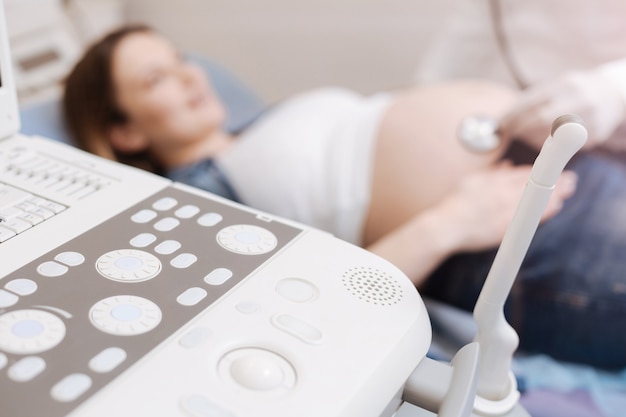 Modern professional ultrasound machine located in the clinic while pregnant patient getting belly examination