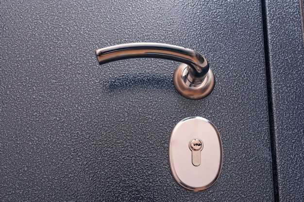 Modern reliable metal entrance door shiny handle lock closeup