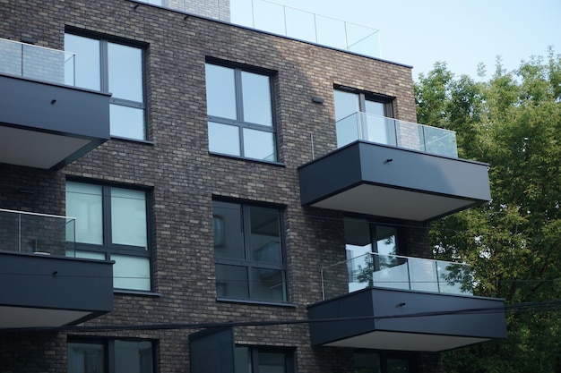 Modern residential building with balconies and dark brick facade Real estate and housing issues concept