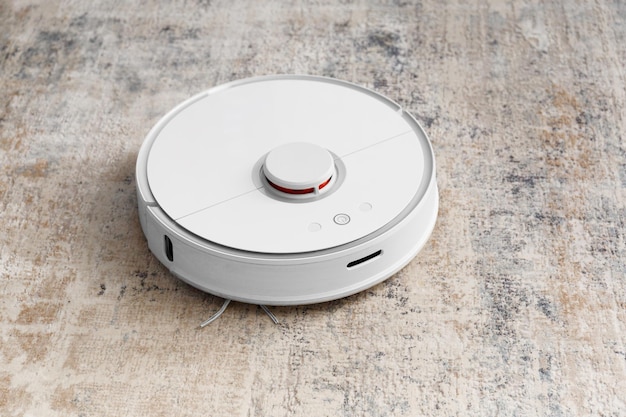 Modern robot vacuum cleaner on soft carpet in room