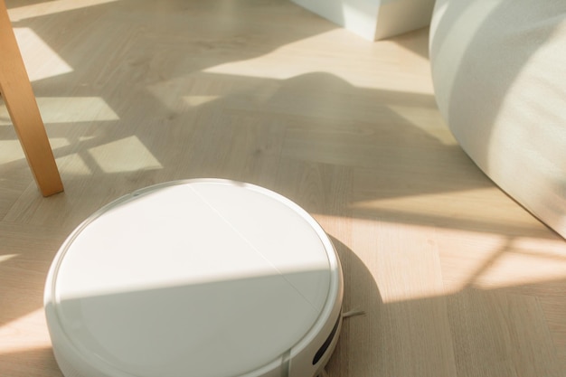 Modern robot vacuum cleaner on wooden floor apartment