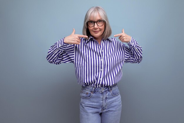 Modern s middle aged woman with gray hair in a stylish look shows her hand at a banner on a bright