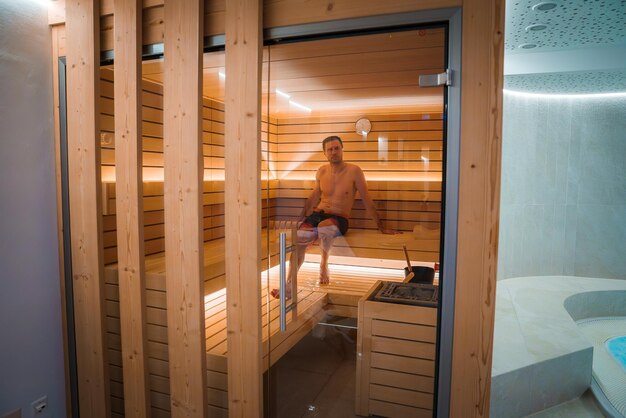 Modern sauna interior with man in swim shorts light wood panels and relaxing atmosphere