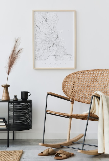 Interiore moderno del soggiorno scandinavo con cornice, comò di design, foglia in vaso, poltrona in rattan, libro e accessori eleganti in un elegante arredamento per la casa.