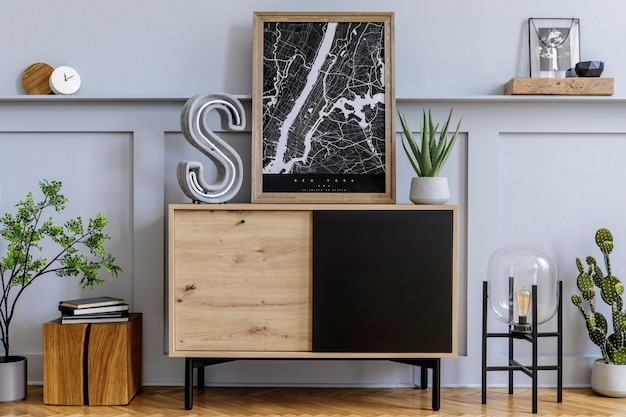 Modern Scandinavisch interieur met kozijnen, design houten commode, grote cementletter, cactussen, planten, decoratie, plank en persoonlijke accessoires in stijlvol interieur.