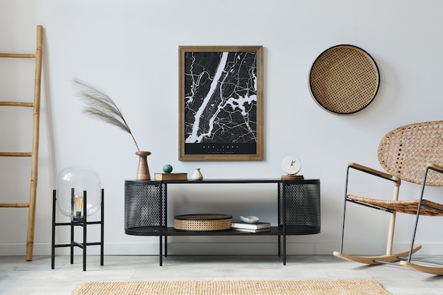 Modern Scandinavisch woonkamer interieur met schilderijlijst, design commode, blad in vaas, rotan fauteuil, boek en elegante accessoires in stijlvol interieur.