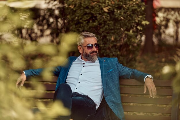 Modern senior businessman resting on a bench in the city on a break from work.