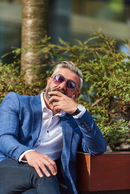 Modern senior businessman resting on a bench in the city on a break from work.