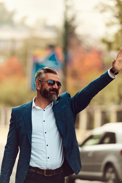 Modern senior businessman stopping a taxi in the city.