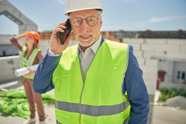 写真 彼の携帯電話が先を見据えて眼鏡をかけた現代の年配の男性