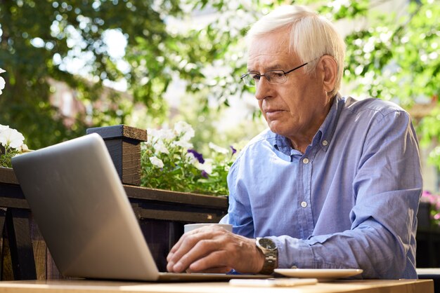 Modern Senior Man Using Laptop in Cafe