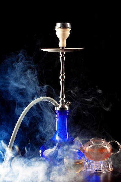 Modern shisha and glass teapot on black background