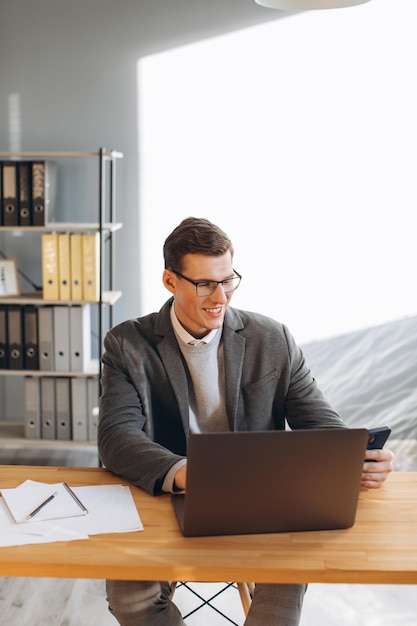 Modern smiling man office worker working on laptop