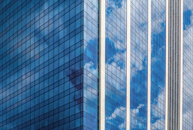 Modern smoked glass office building against a blue cloudy sky