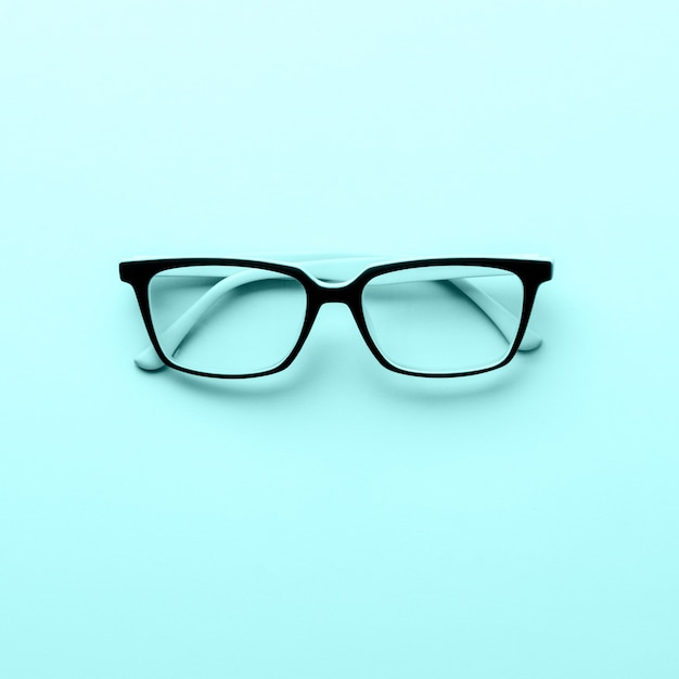 Modern spectacles eye glass isolated on blue surface.