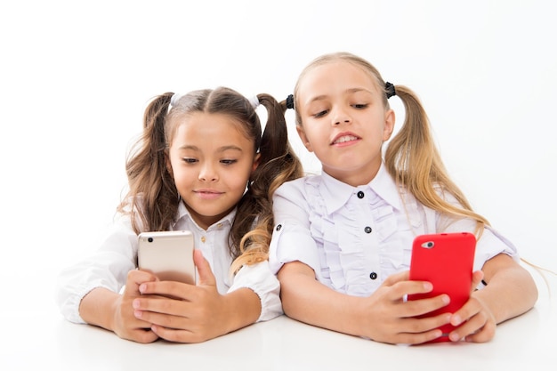 Modern students Small students using mobile phones in classroom isolated on white Little students texting message during class Cute lyceum students diving deep into smartphone lessons