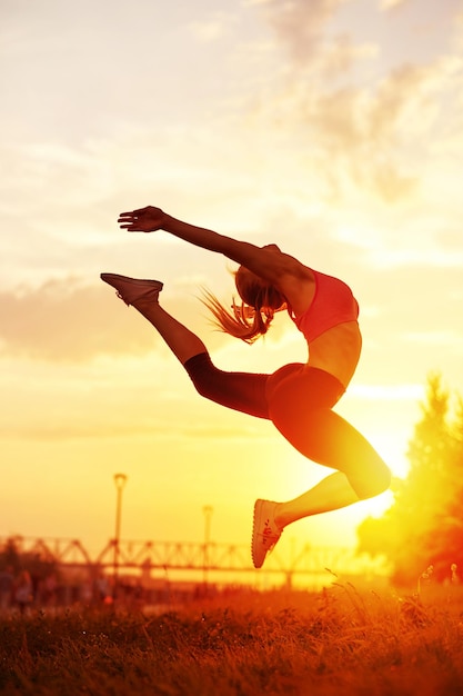 Modern style dancer woman jumping Dancer silhouette at sunset Contour of girl on urban city background