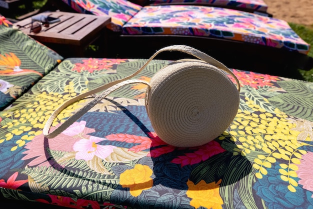 Modern stylish round straw bag isolated on the sunbed top view